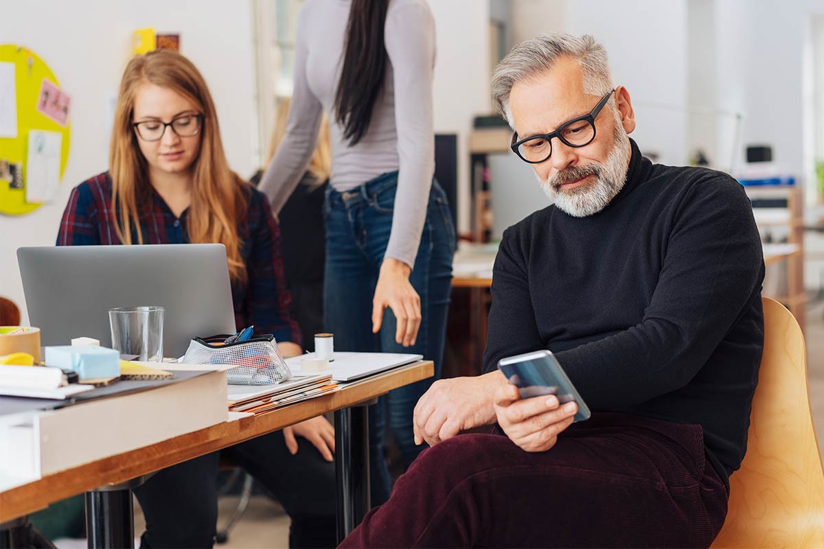 Man and woman reading news and updates on their smartphone and laptop