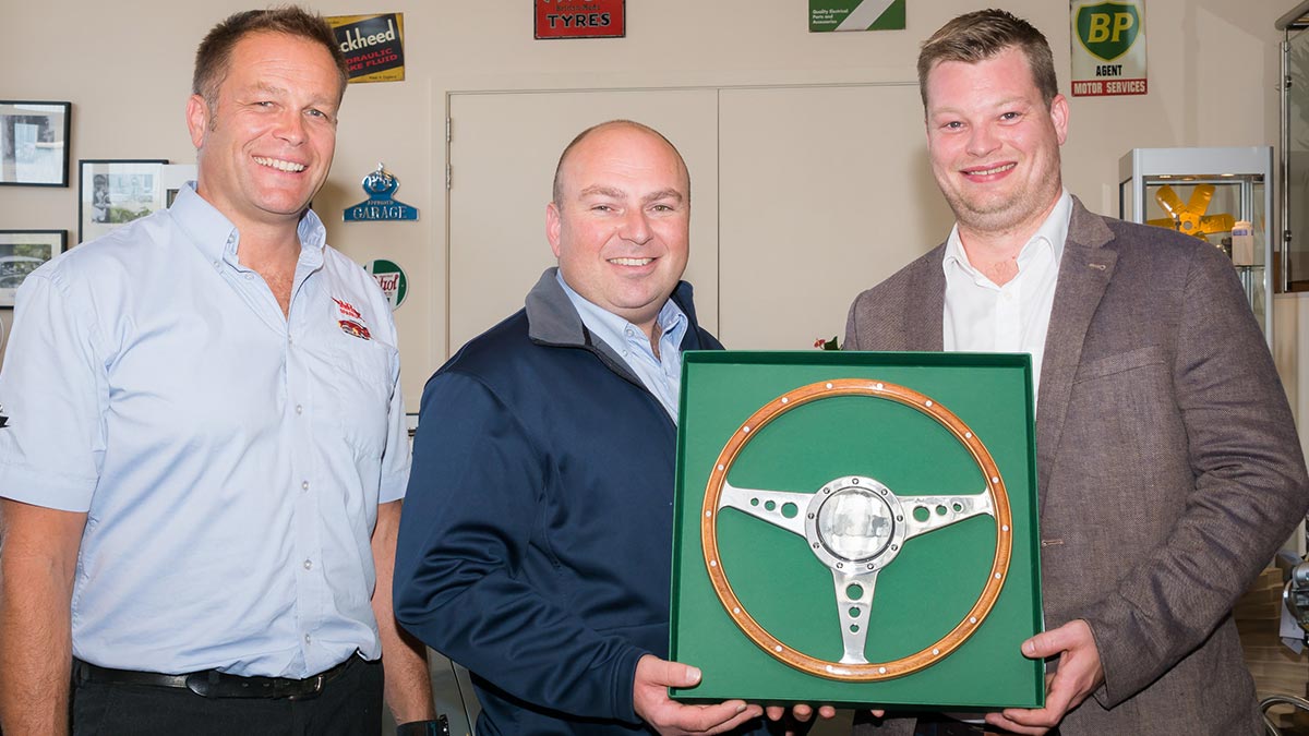 Marcus Poole from Moto-Lita presenting the 60th anniversary commemorative Moto-Lita steering wheel to Jonathan Hill and John Lee.