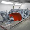 Austin Healey BJ8 chassis in primer and red paint inside spray booth at JME Heal