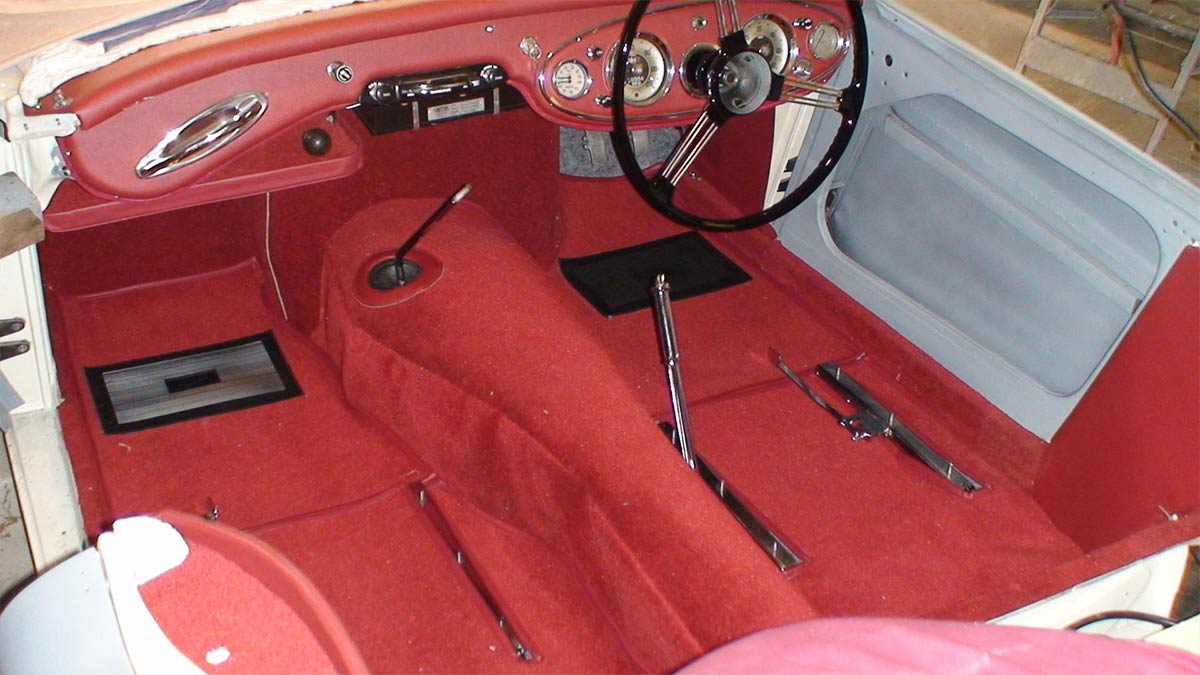 Restored interior of an Austin Healey 100/6 with new red carpets.