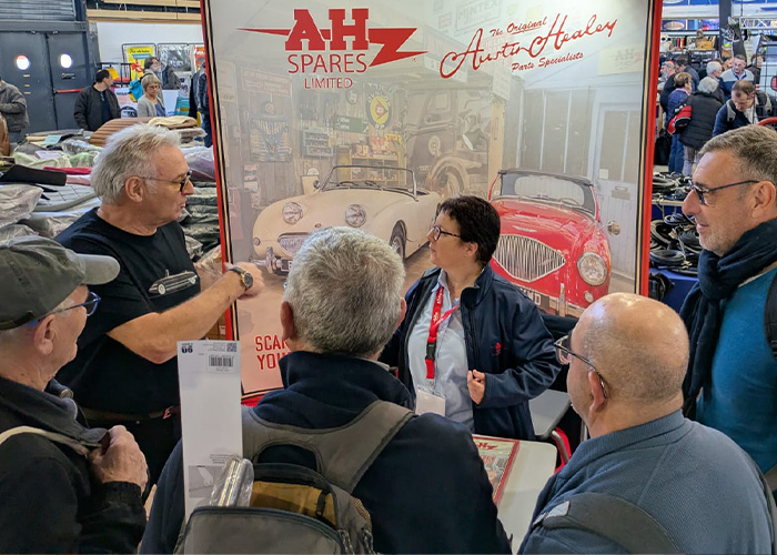 Patricia from A H Spares speaking with Austin Healey enthusiasts at the Époqu’Auto Lyon 2025 classic car show.