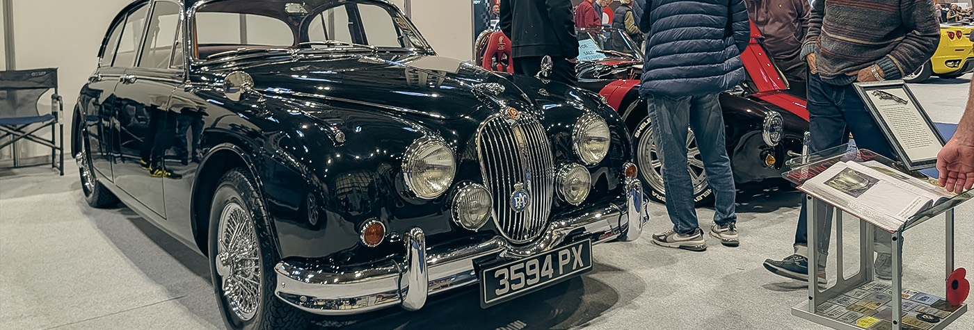 Restored black Jaguar saloon on display at the NEC Classic Motor Show 2025 alongside other British classics and sports cars.