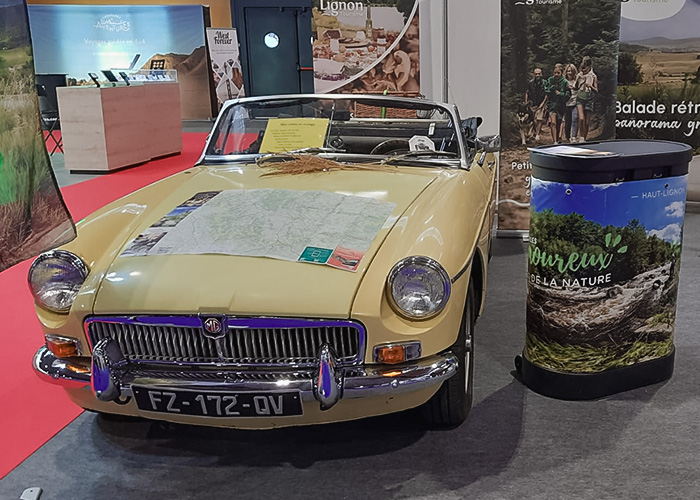 Yellow MG convertible on display at Époqu’Auto Lyon 2025 featuring a touring map across the bonnet.