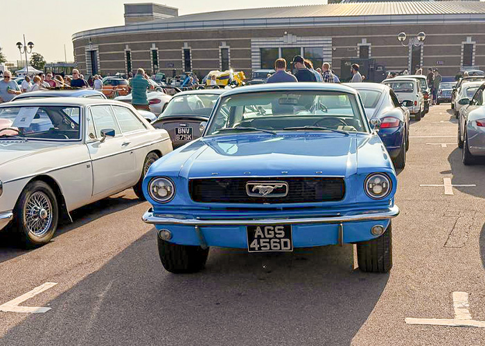1960s Ford Mustang coupe in light blue at the British Motor Museum’s Gaydon Gathering, surrounded by vintage cars.