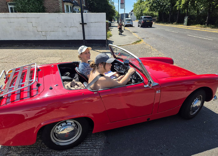 Red Austin Healey Sprite departing