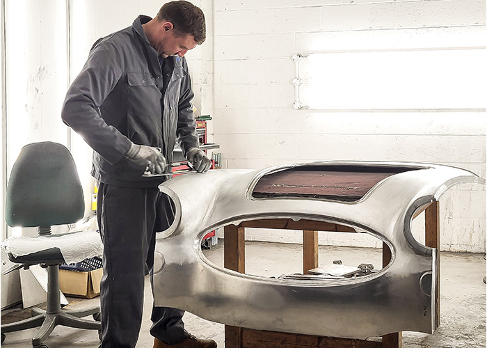 Technician at A H Panels shaping a front shroud for an Austin Healey 3000 BJ8 restoration.