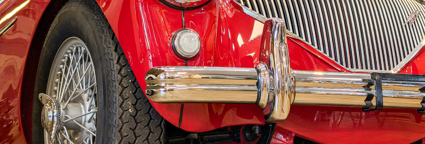 Chrome bumper over-rider fitted to a red Austin Healey 100