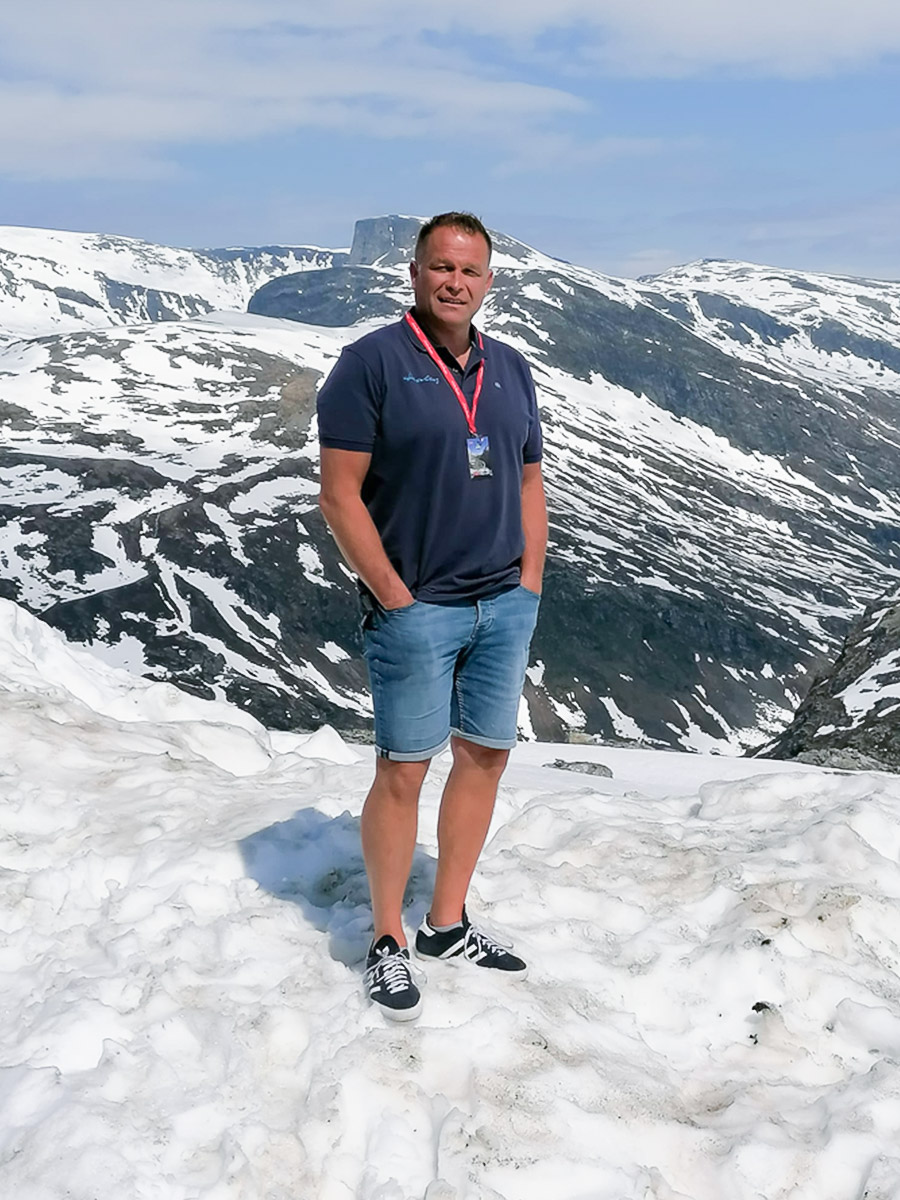 A H Spares Business and Development Director John Lee standing on a snowy mountain in Norway near the Dalsnibba Skywalk at the 6th European Healey Meet 2023