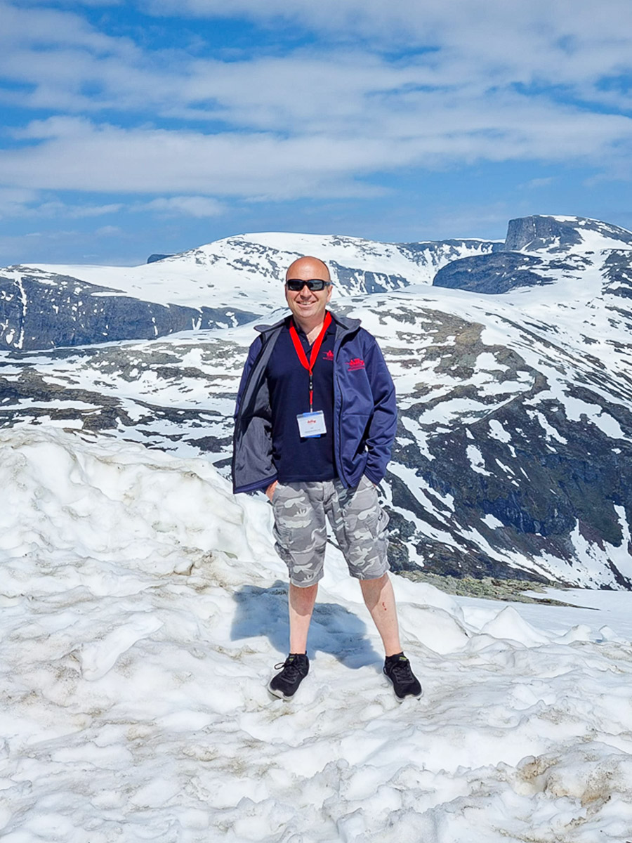 A H Spares Managing Director Jon Hill standing on a snowy mountain in Norway near the Dalsnibba Skywalk at the 6th European Healey Meet 2023