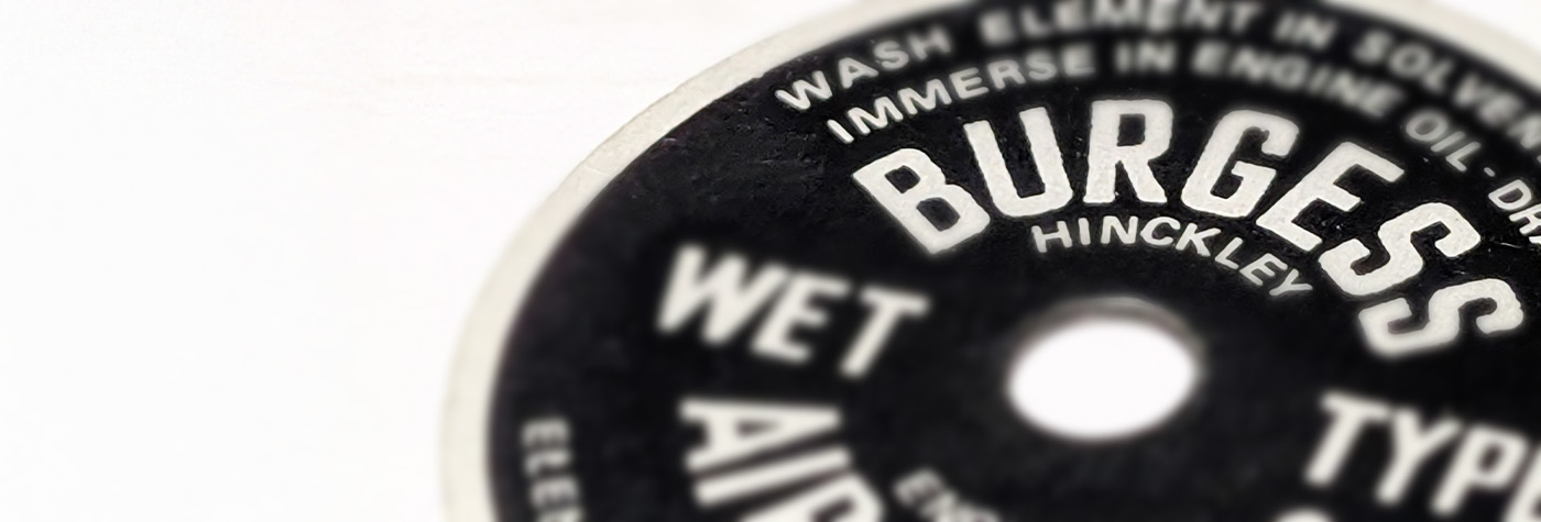 Close-up of Burgess Air Filter plaque for Austin Healey 100, showing original Hinckley lettering and period satin-black finish.