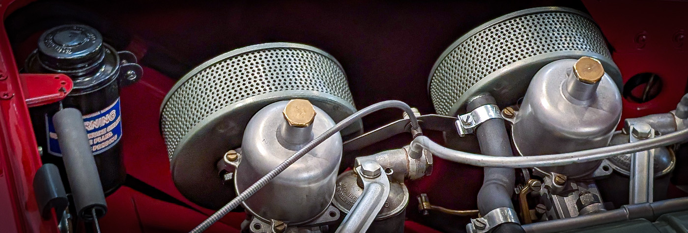 Front and rear Burgess air filters inside Austin Healey 100 BN1 engine bay showing correct green-grey enamel finish.