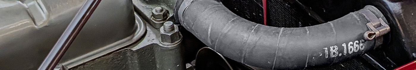 Close-up view of a top radiator hose fitted to a classic Austin Healey BN1 engine bay, showing authentic hose markings and detailing.