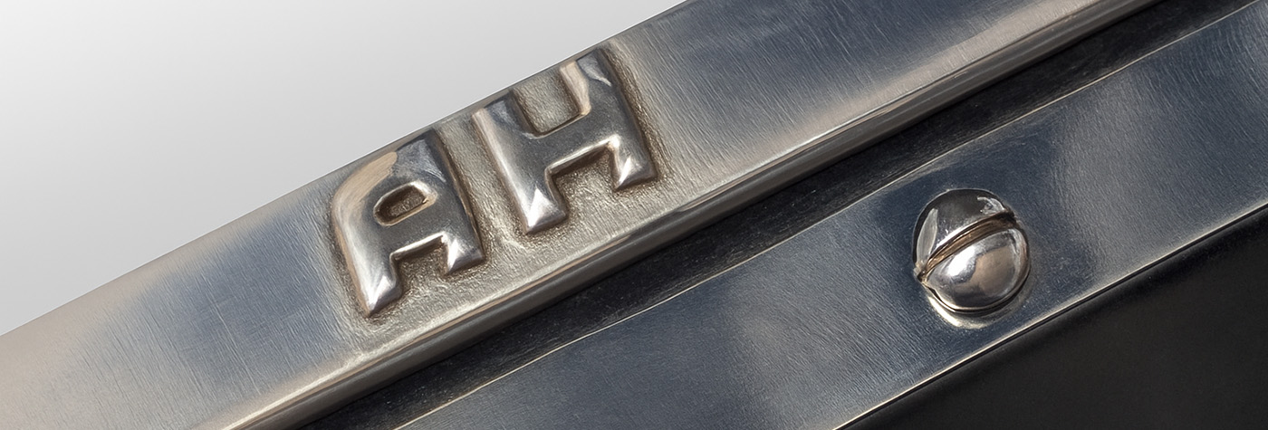 Close-up of the raised AH cast into the aluminium frame and one of the slotted chrome screws on the factory-correct reproduction aero screen for the Austin Healey 100M and 100S.