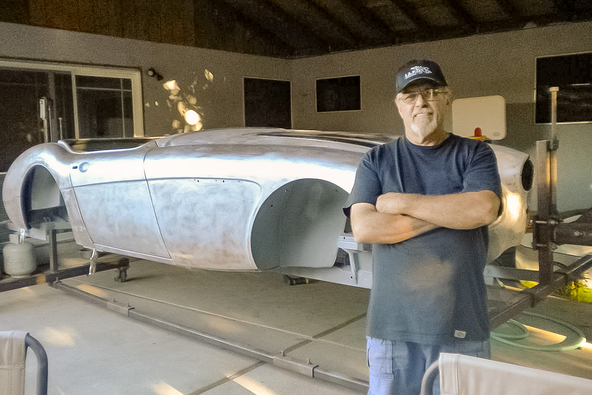 Owner standing beside the bare-metal body of the 1961 Austin Healey 3000 during restoration