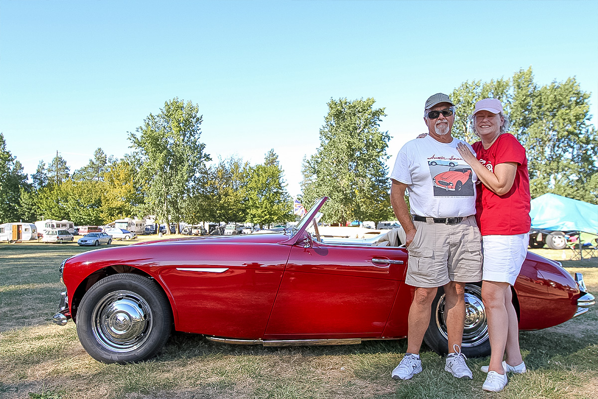 Owner and companion standing beside the completed dark red 1961 Austin Healey 3000